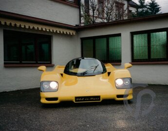 Dauer 962 Le Mans in gelb in der Frontansicht mit geschlossenen Flügeltüren auf dem Werkstattgelände